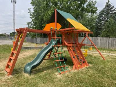 Woodplay playset with monkey bars, slide, rock wall, and vinyl roof